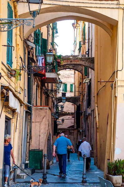 Ludzie spacerując wąską starożytną średniowieczną ulicą starego miasta pełną łuków w Sanremo, Włochy. — Zdjęcie stockowe