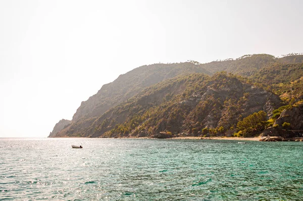 Човни біля скелястого узбережжя з високими зеленими горами і променями сонця ззаду на задньому плані в Монтероссо Аль-Маре, Cinque Terre — стокове фото