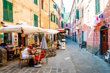 İnsanlar Monterosso Al Mare, Cinque Terre, İtalya 'nın zemin katındaki küçük işletmelerle dolu rahat ve hareketli caddelerde yürüyorlar.