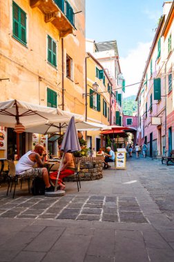 İnsanlar Monterosso Al Mare, Cinque Terre, İtalya 'nın zemin katındaki küçük işletmelerle dolu rahat ve hareketli caddelerde yürüyorlar.