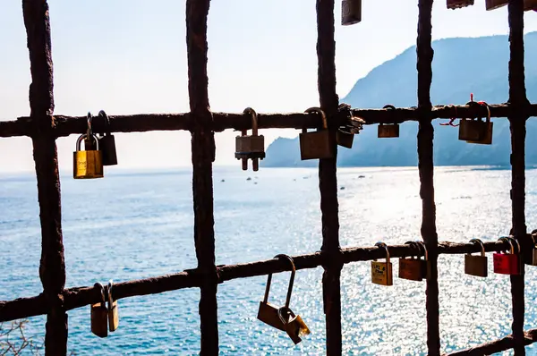 Любовь и брак замки висят на металлической решетке окна в Монтероссо Аль Маре с красивым морским пейзажем на заднем плане — стоковое фото