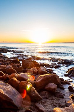 Günbatımında Cala Violina manzaralı kayalık plaj manzarası. Güneş ufukta batıyor. Günbatımında Tyrhenian Deniz Koyu.