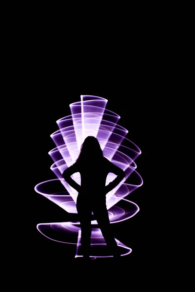 鉛の光を持つ女性のシルエット ライトセーバーバイオレットで作られた曲線抽象的な形状 夜のライトペインティング — ストック写真