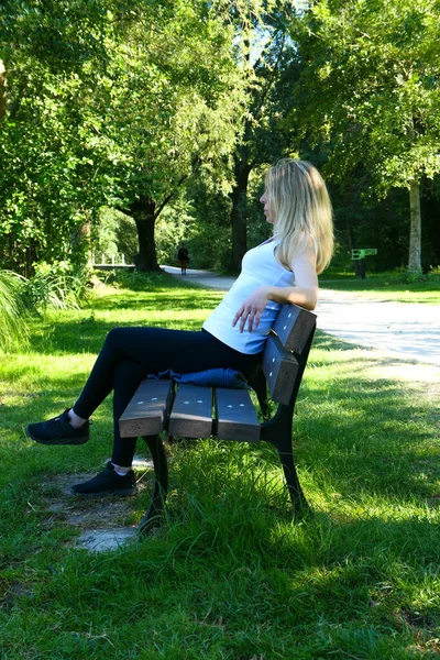 金发女人坐在面对湖面的乡村景色的长椅上 孤独的女性在大自然的平静中放松 故意模糊背景 — 图库照片