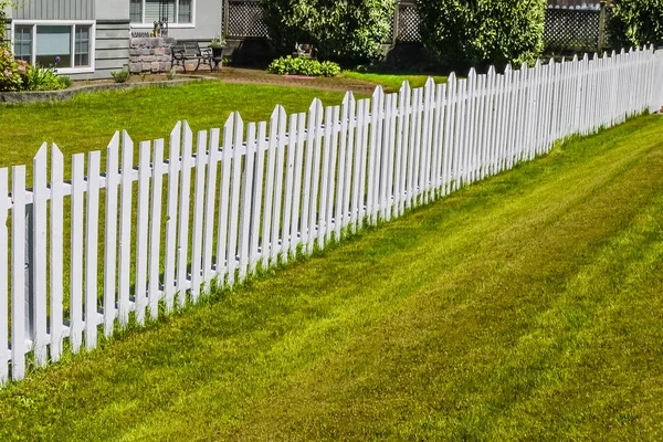 住宅の前庭に沿って白い長い木製のフェンス — ストック写真