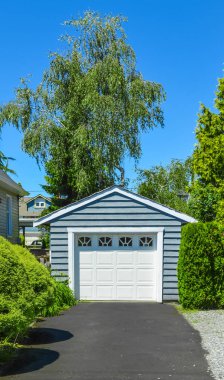 Asfalt driveway ile bir arka bahçesinde tek garaj boyunca stand.