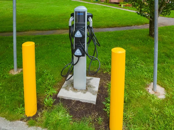 Elektromos autó töltési pont telepítve a zöld pázsit sárga pillér körül — Stock Fotó