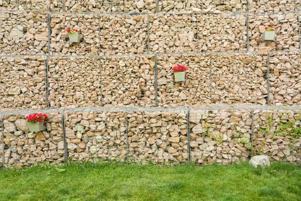 Габіон огорожа стіна зі сталевої сітки з камінням прикрашені квіти . — стокове фото