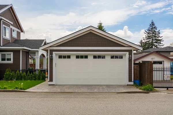 Detached garage of residential house with asphalt road in front.