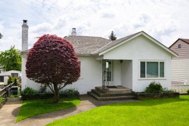 Önünde yeşil çim ve dekoratif ağaç ile küçük aile evi