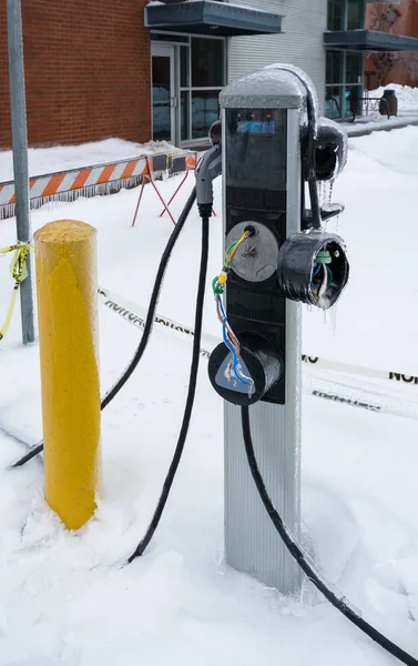 Ice covered EV charging station in disrepair on winter season