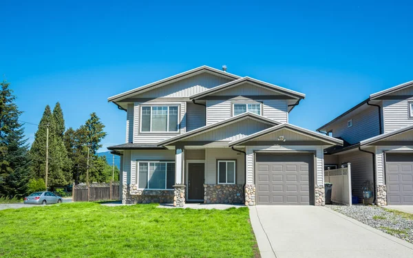 Önünde beton sürücü yolu ve yeşil çim ile yarım dubleks konut binası