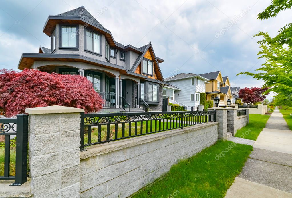 Row of residential houses with concrete pathway and metal fence in front