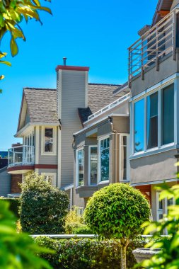 Güneşli bir günde peyzajlı bahçeli evlerin önü.