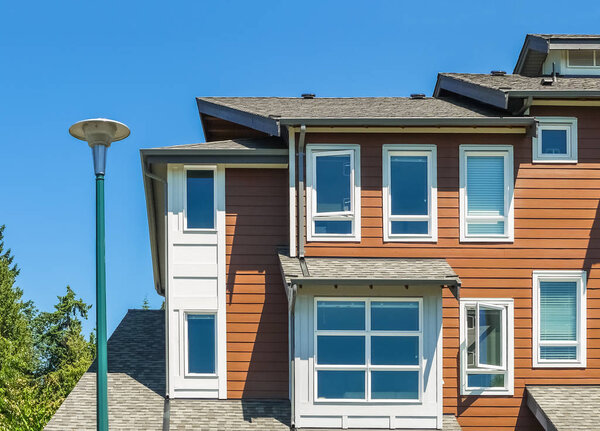 Corner of new townhouse with street light pole in front on blue sky background