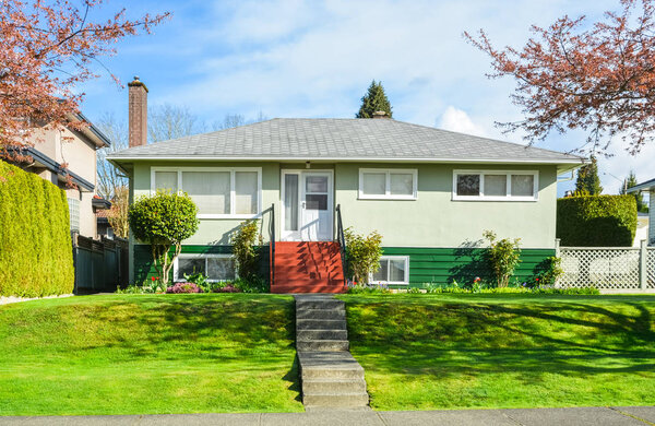 Жилой дом с ландшафтным двором на голубом фоне неба
