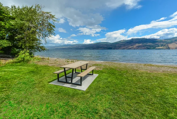 Picnic area with table and benches on a shore of Okanagan lake