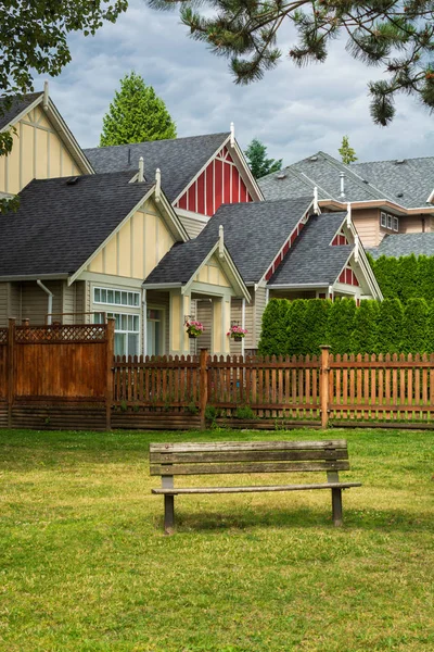 Bunte Wohnhäuser mit Holzbank auf Parkwiese in der Nähe. — Stockfoto