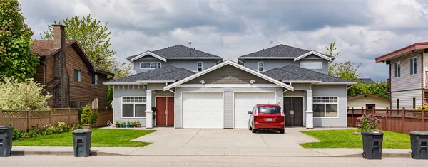 Residential duplex townhouse with red car parked on concret driveway — Stock Photo, Image