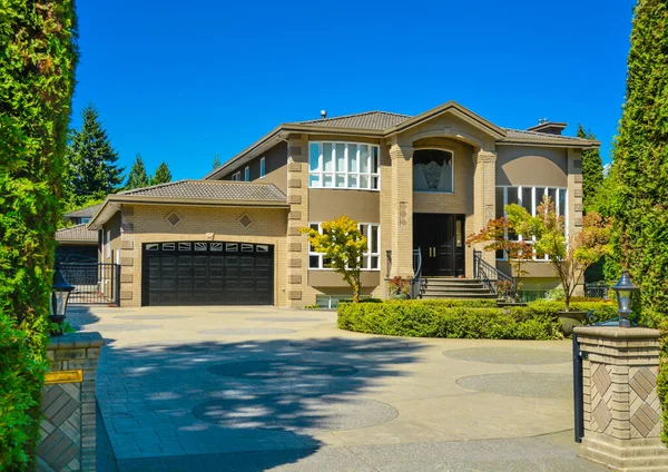 Front yard of luxury family house with paved driveway on blue sky background