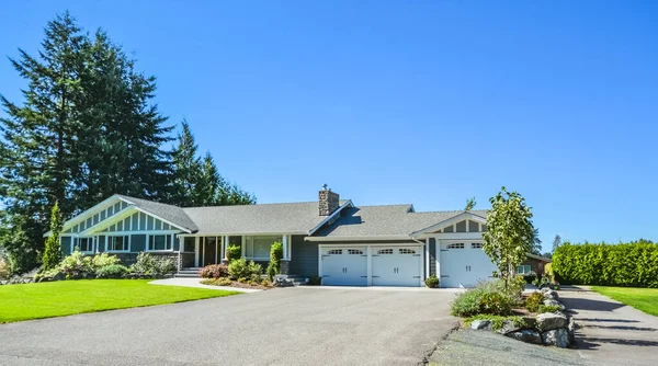 Wide asphalt driveway of residential house with three door garage attached — Stock Photo, Image