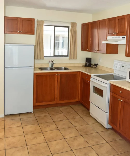 Small kitchen with wooden cabinets, fridge, and electric stove