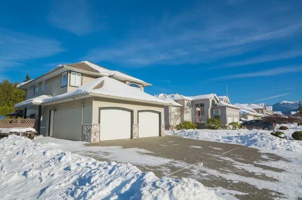 Double garage of big luxury house with driveway and front yard in snow — Stock Photo, Image