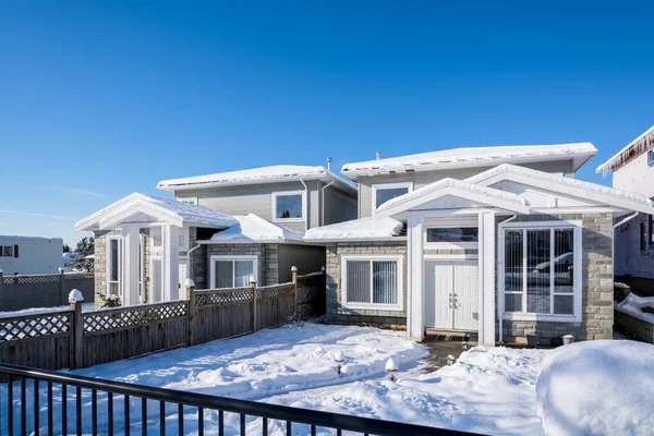Residential duplex house with front yard in snow on bright winter day in Canada
