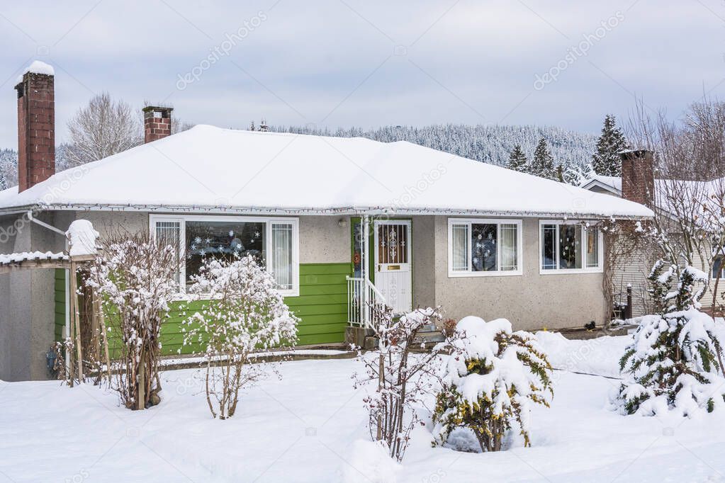 Colorful residential house in snow on winter cloudy day