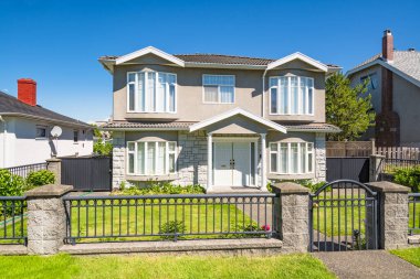 Önünde demir çit olan büyük bir ev..