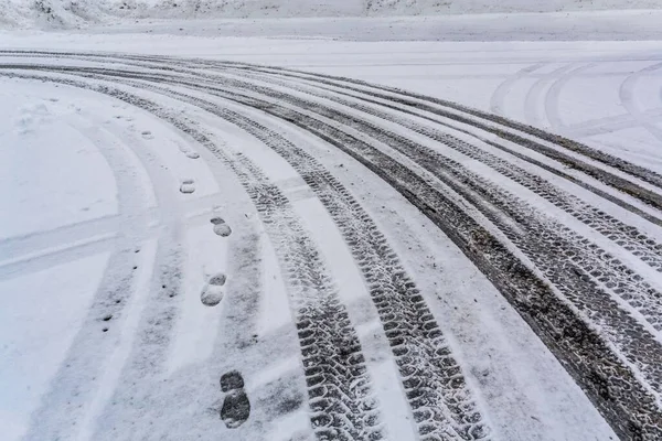 Следы шин на снегу с человеческими следами рядом . — стоковое фото