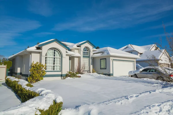 Duży luksusowy dom mieszkalny z zaparkowanym samochodem na podjeździe i podwórku w śniegu — Zdjęcie stockowe