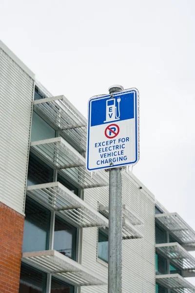 Panneau de borne de recharge EV dans les glaces avec immeuble de bureaux sur le fond — Photo