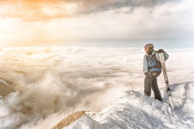 Snowboarder elinde snowboard ile kalmak dağlar arka planda büyük kaya üzerinde oturur. Bansko, Bulgaristan