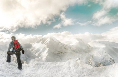 Snowboarder elinde snowboard ile kalmak dağlar arka planda büyük kaya üzerinde oturur. Bansko, Bulgaristan