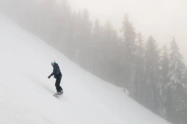 Snowboarder descend d'une haute montagne sur une pente par temps froid d'hiver — Photo