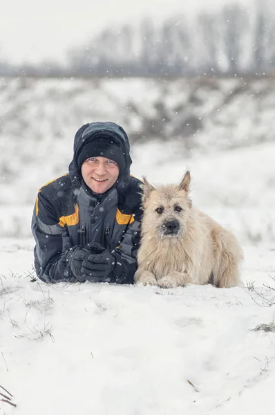 Homme et chien sont heureux couchés dans la neige d'hiver — Photo