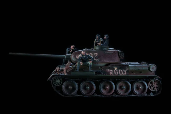 Model of the Russian tank T-34 fighting vehicle, with three soldiers nearby. Black background — Stock Photo, Image
