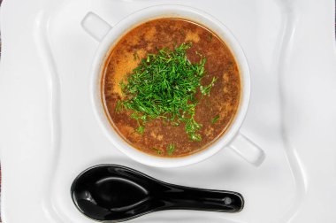Bir kase de taze sebze ile lezzetli iştah açıcı çorba masada ve siyah kaşık servis edilir. Yukarıdan yakın çekim