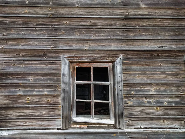 Окно старого деревянного бревенчатого дома на фоне деревянных стен — стоковое фото