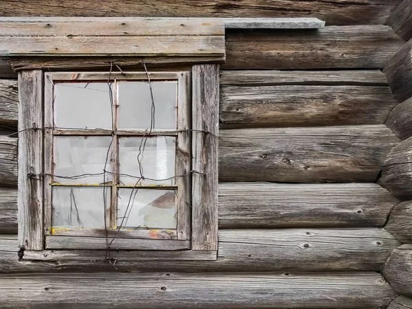 Das Fenster des alten Blockhauses auf dem Hintergrund der Holzwände — Stockfoto