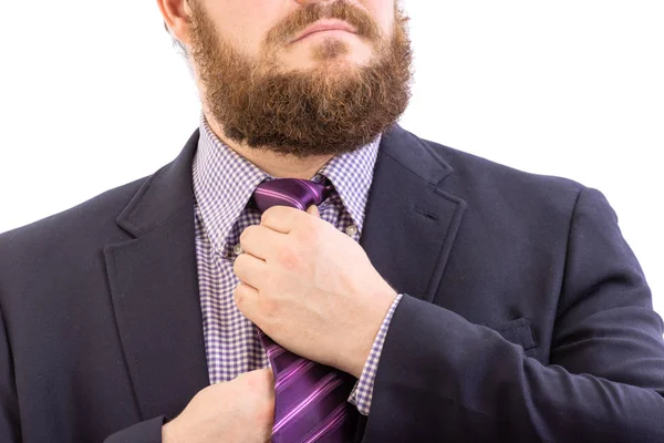 特写 一位身着深色西装的帅胡子商人拉直亮蓝色领带，与白色隔离的肖像 — 图库照片