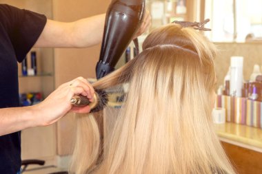 Closeup berber kuaför kuru sarı saç kurutma makinesi bir güzellik salonunda. güneş ışığı ile arka görünüm