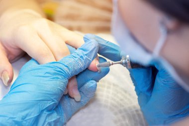 Bir güzellik salonunda closeup donanım manikür. Manikürcü parmaklarında manikür için elektrikli tırnak dosyası matkap kullanın.