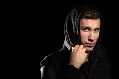 Kapüşonlu siyah arka planda genç bir adamın portresi