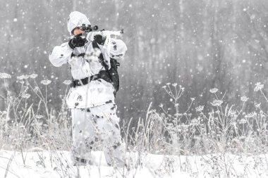 Beyaz kış kamuflaj bir keskin nişancı tüfeği ile bir avı kışın adam asker karda ayakta amaçlayan