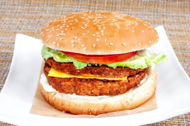 Beyaz bir tabakta siyah ekmek ve taze sebze ile Klasik hamburger.