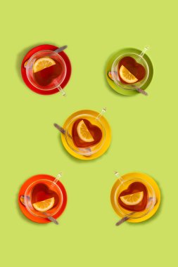 Doku birkaç Fincan siyah çay kalp şeklinde fincan ve kırmızı tabak, yeşil arka plan üzerinde üst görünümü