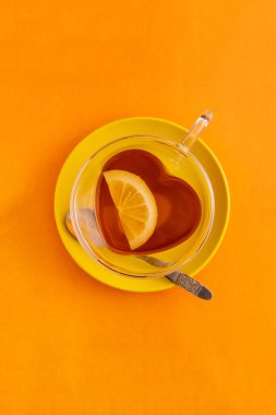 Fincan siyah çay kalp şeklinde fincan ve sarı tabak, üst görünümü veya