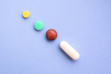 Mavi arka planda birkaç farklı hap türleri ve renkleri